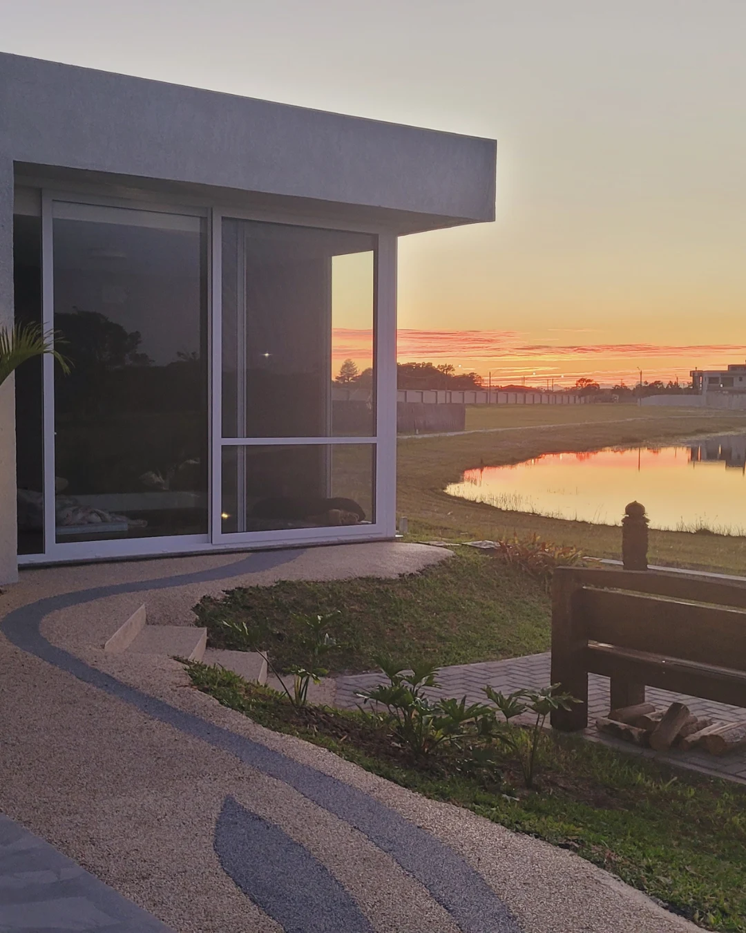 Esquadrias da residência ao entardecer com vista para o lago