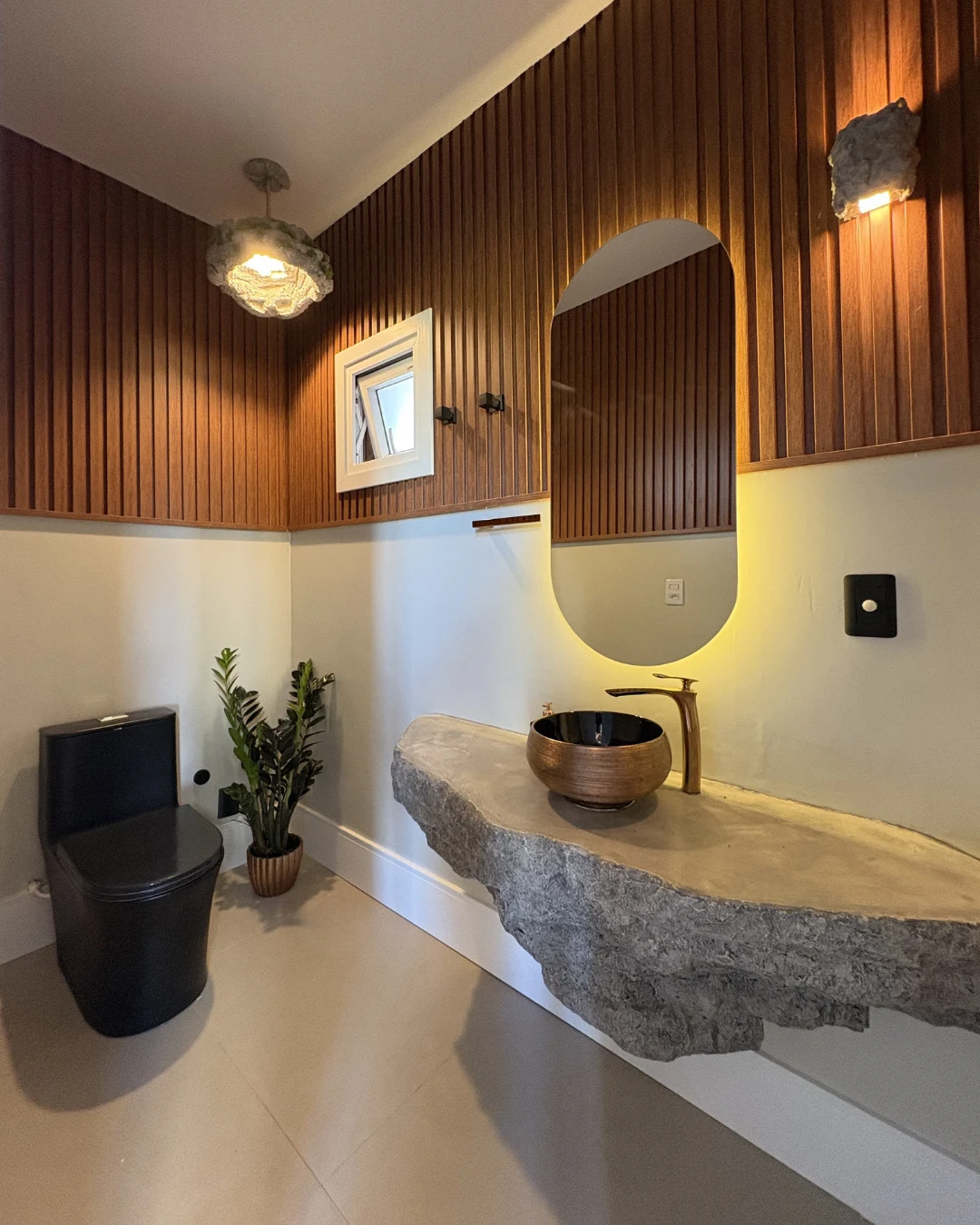 Lavabo com cuba rústica em pedra e revestimento em madeira