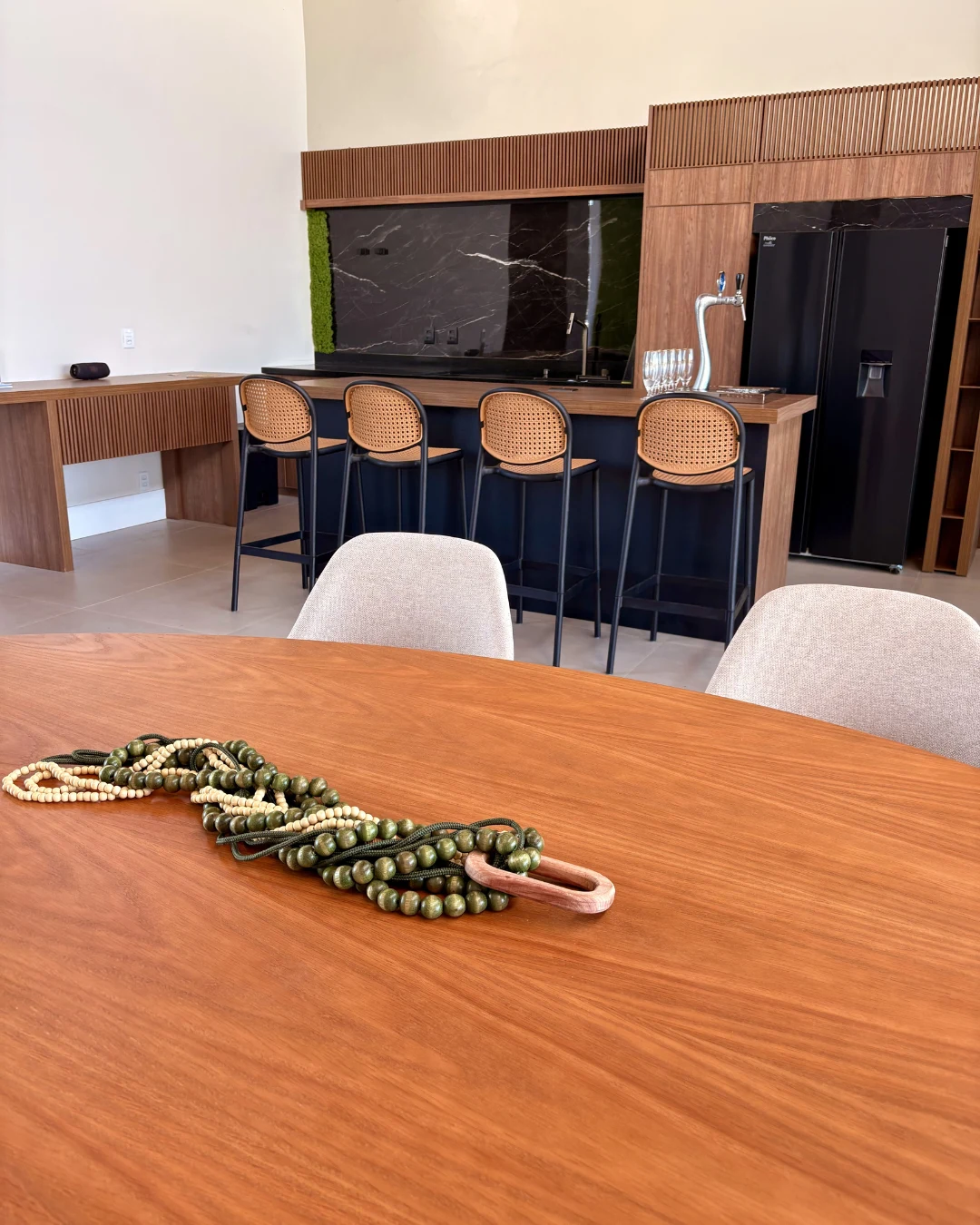 Espaço gourmet com bancada, chopeira e acabamentos em madeira